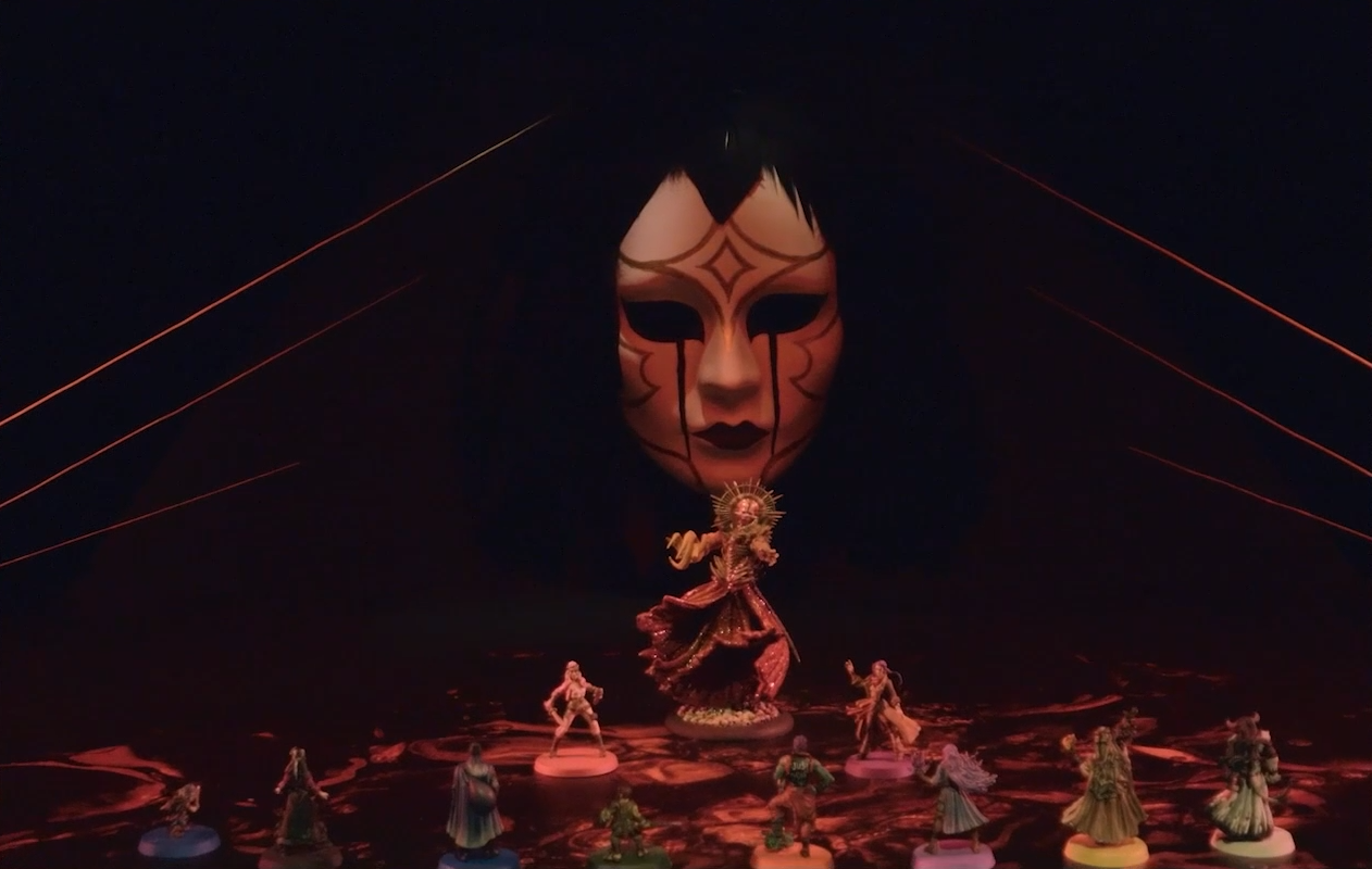 A battlemap depicting a floor of glowing red blood looked over by a patterned porcelain mask with hair of black feathers. Chetney, Laudna, Dorian, Orym, Ashton, Imogen, Fearne, and Braius stand in a line facing off against Opal, Liliana, and a giant Vespin Chloras between them. Six golden strands run from behind the mask to the edges of the floor.