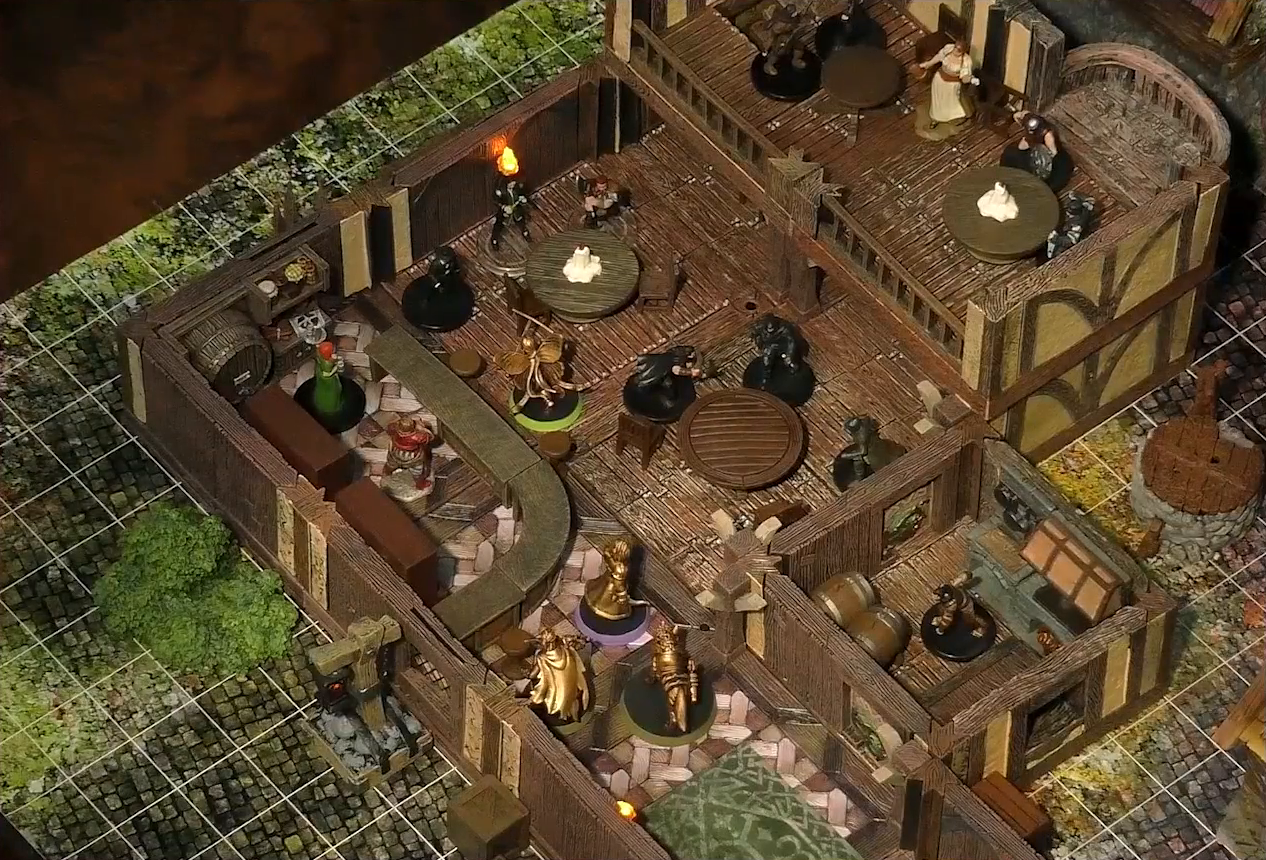 A battlemap of the interior of a wooden tavern. A number of black-cloaked individuals and other rogues stand near round tables, facing off against Thimble, Occtis, Kattigan, and Wulfric. Two bartenders, one thin and in a green dress, one stout and burly, stand behind a countertop. A small side room houses brick stoves, barrels, and a long-armed, beast-like individual. An upper level of the tavern has more tables, rogues, and an individual in a white dress who appears to be a server. A covered well sits outside the tavern.