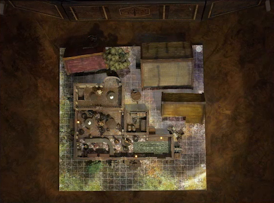 A top-down view of a battlemap of a wooden tavern with a couple small shed-like buildings next to it. A number of black-cloaked individuals and other rogues stand near round tables, facing off against Thimble, Occtis, Kattigan, and Wulfric. Two bartenders stand behind a countertop. A small side room houses brick stoves, barrels, and a long-armed, beast-like individual. An upper level of the tavern has more tables, rogues, and an individual in a white dress who appears to be a server. A covered well sits outside the tavern.