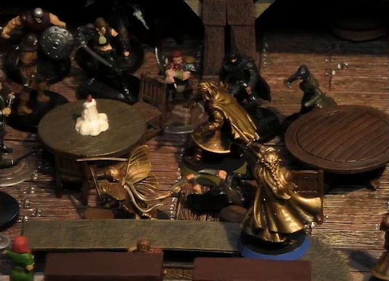 A battlemap of the interior of a wooden tavern focused on Thimble, Kattigan, and Vaelus facing off against a number of black-robed individuals and other rogues. One rogue in the middle of the heroes lays on the ground. They fight amongst round tables, one of which has a melting white candle in the center. Two bartenders watch from the other side of a counter, on which Vaelus stands.