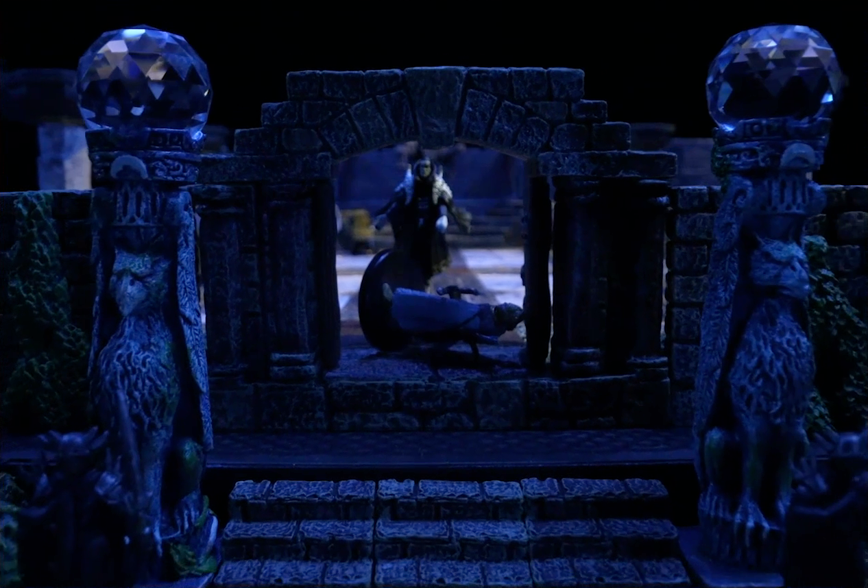 A battlemap of a stone palace focused on the entrance. Two stone pillars bearing carvings of griffins and topped with large spherical crystals frame the entryway. In the background, a stony-faced Primus Tachonis stands in the entryway over a fallen guard. Behind him inside the palace is a marble floor and a number of scattered individuals.