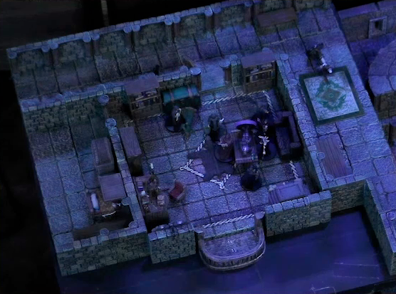 A battlemap of a stone palace upper floor. Occtis lays on a wooden table in a small room with a bearskin rug and balcony, surrounded by a number of robed individuals including Ethrand Tachonis. Aranessa lays on the ground by the door, next to another robed individual. A fallen guard is outside the room, down the hall.