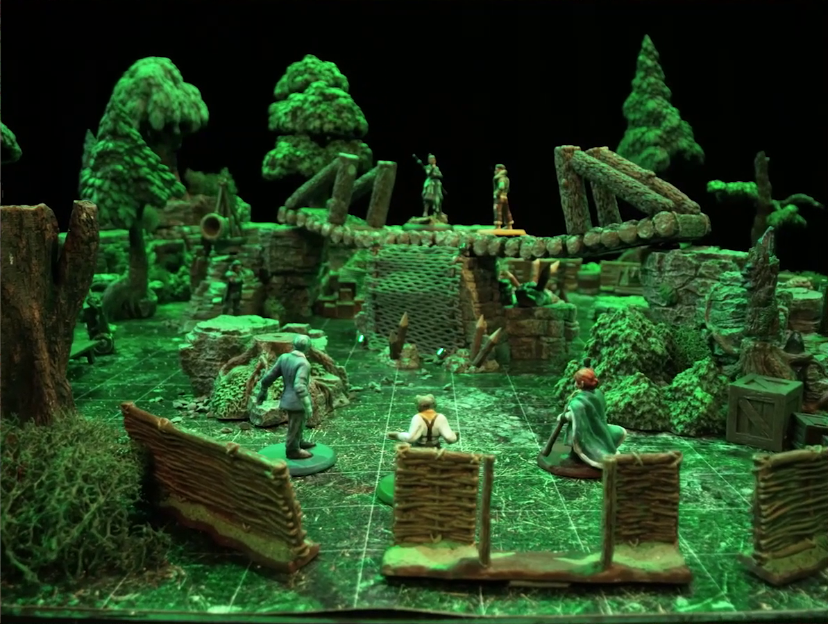 A battlemap of a forest clearing. Jessep, Padmund, and Sky stand in the foreground in front of a wooden fence. They look at a log bridge spanning two stone ledges raised above the forest floor, on which Beau and Kai are standing. Yasha is on the ground near Beau’s end of the bridge. A net of climbable-looking ropes leads up from the ground to the bridge’s center, and wooden stakes sprout from its base.