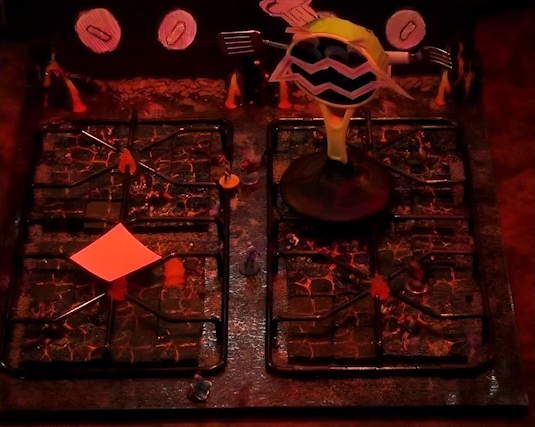 A battlemap that looks like a stovetop. Wok Wok, the giant frying pan creature, stands between the front and back right burners. Jessep, Kai, Sky, Padmund, Beau, and Yasha are spread across the rest of the stove. The front right burner has a pink sticky note on it. Small flames sprout from each of the four burners and four knobs are on the back panel. The base of the battlemap looks like magma and the scene is bathed in red light.