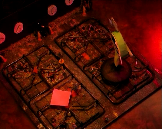 A battlemap that looks like a stovetop. Wok Wok, the giant frying pan creature, stands on the front right burner. Jessep, Kai, Sky, Padmund, Beau, and Yasha are spread across the rest of the stove. The front right burner has a pink sticky note on it. Small flames sprout from each of the four burners and four knobs are on the back panel. The base of the battlemap looks like magma and the scene is bathed in red light.