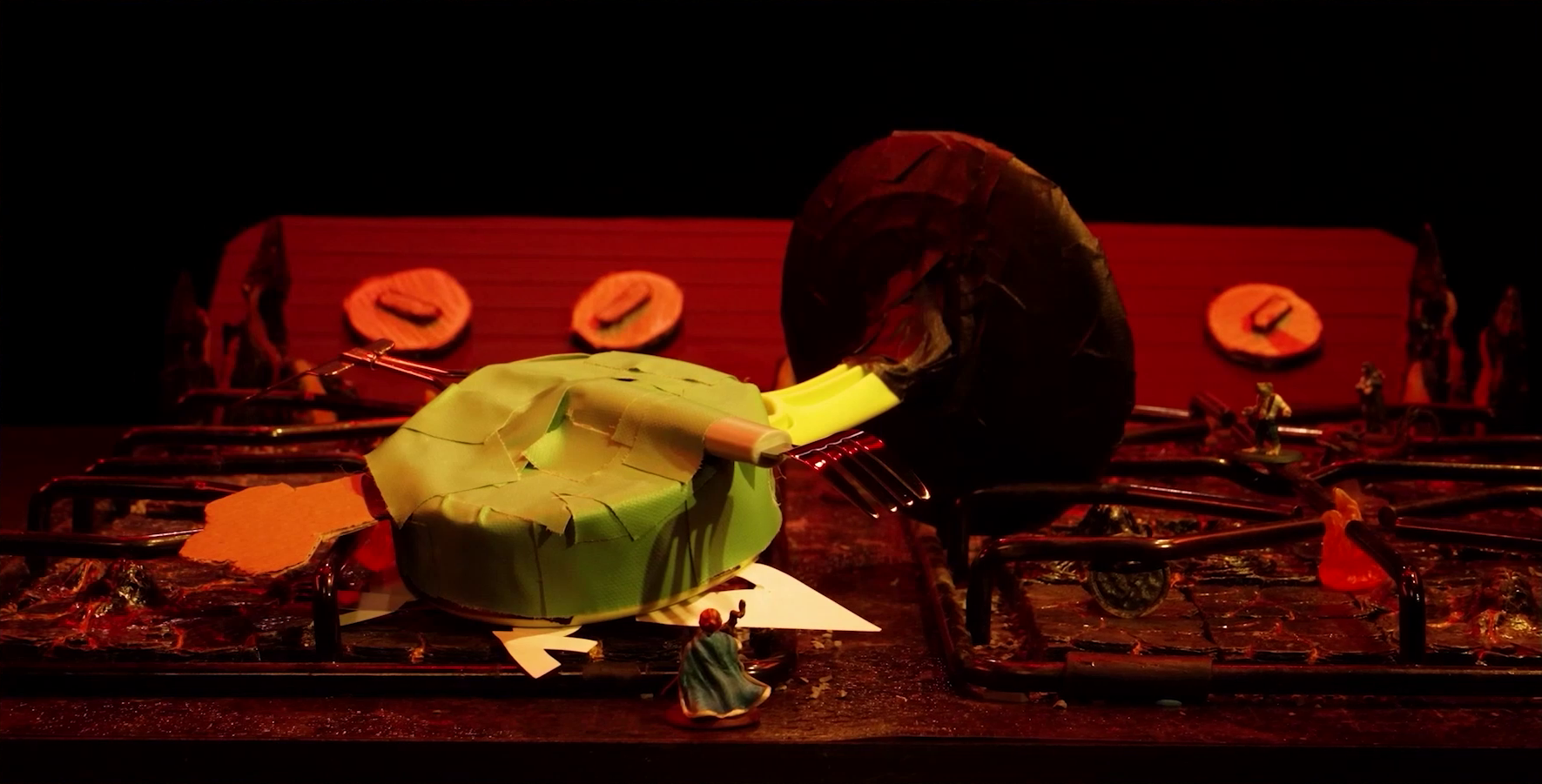 A battlemap that looks like a stovetop. Wok Wok, the giant frying pan creature, lies face-down across the burners. Sky stands in the foreground facing it, while Padmund and Yasha are visible in the background. Small flames sprout from each of the four burners and four knobs are on the back panel. The base of the battlemap looks like magma and the scene is bathed in red light.