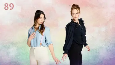 Thumbnail for episode 89. Laura and Marisha stand side-by-side, looking thoughtfully at their lowered hands drifting towards each other. Their index fingers are slightly extended so their hands almost touch. Laura is dressed in a sky blue button-up shirt under pink suspenders, tucked into white pants. Marisha wears all black, with a frilly blouse and jeans. They stand against a colorful backdrop, with splashes of reds, oranges, yellows, greens, blues, and purples in a rainbow sequence.