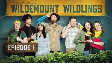 Thumbnail for episode 1. A group photo of Marisha, Aleks Le, Libe Barer, Sam, Brennan Lee Mulligan, Eden Riegel, and Ashley standing in a line dressed in outdoorsy camp clothes. Sam wears a tan scout uniform and Marisha and Ashley wear “Camp Counselor” T-shirts. All sport yellow bandanas except Sam. Text at the top of the image on a large fabric banner reads “Critical Role Presents Wildemount Wildlings” and bushes line the bottom of the image. Marisha and Aleks give thumbs up (Marisha looking nervous), Libe holds her hair and looks out calmly, Sam salutes goofily, Brennan places fingers to temples as if thinking hard, and Ashley puts her arm around Eden’s shoulder, both smiling and gesturing at each other.