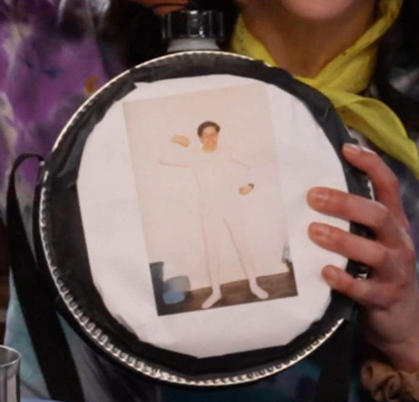 A circular canteen with a screw top. An image of a teenage Sam Riegel in white long underwear is printed on a white sheet of paper taped to the front. Sam flexes his arms and bears his teeth. Eden Riegel is holding it just out of frame.