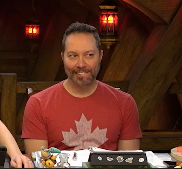 Sam wearing a red T-shirt with a faded white maple leaf on the center of the chest. Sam is looking to his left and biting his lower lip.